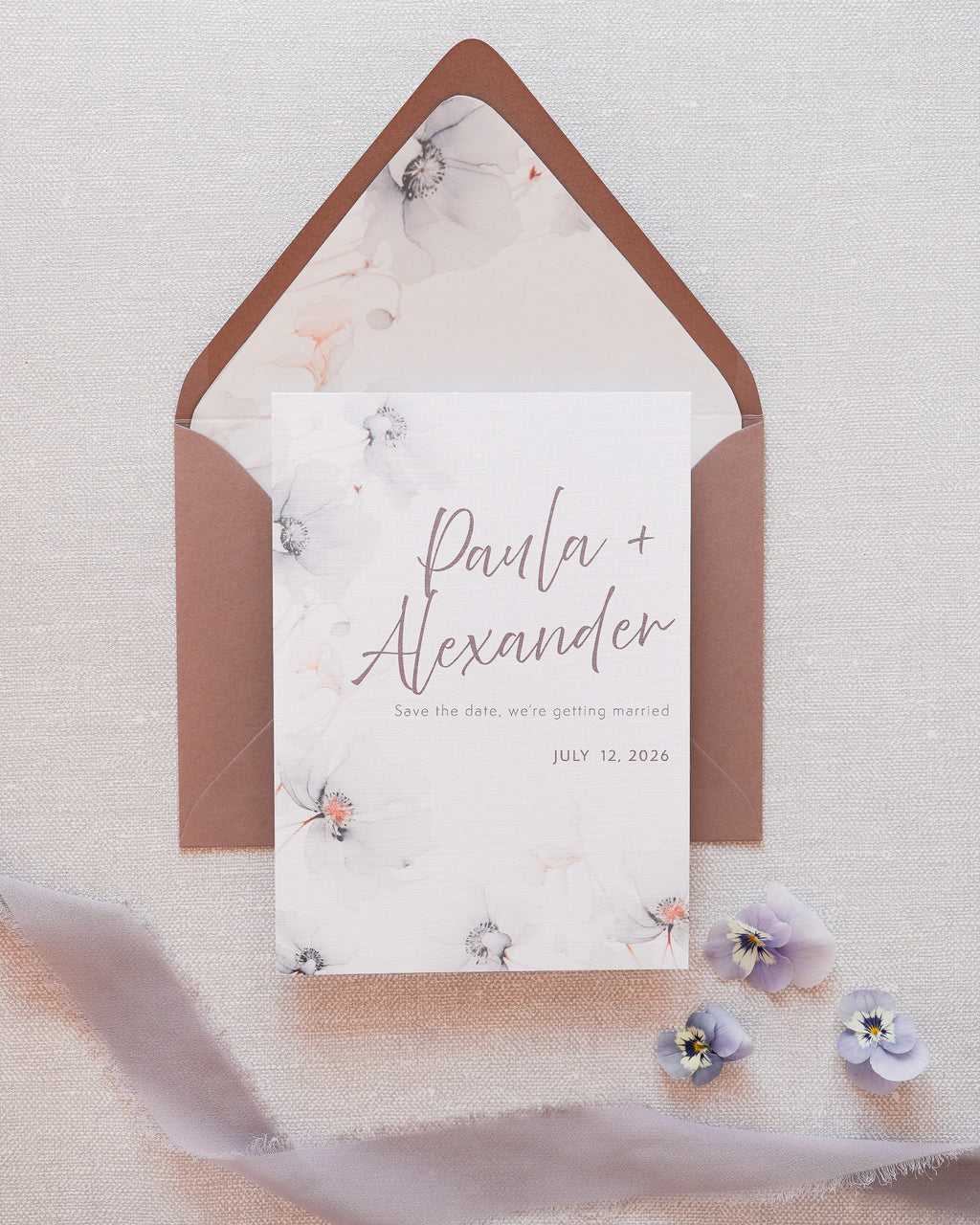 A save the date card in a grey floral print. Matched with a grey envelope with a floral printed liner.