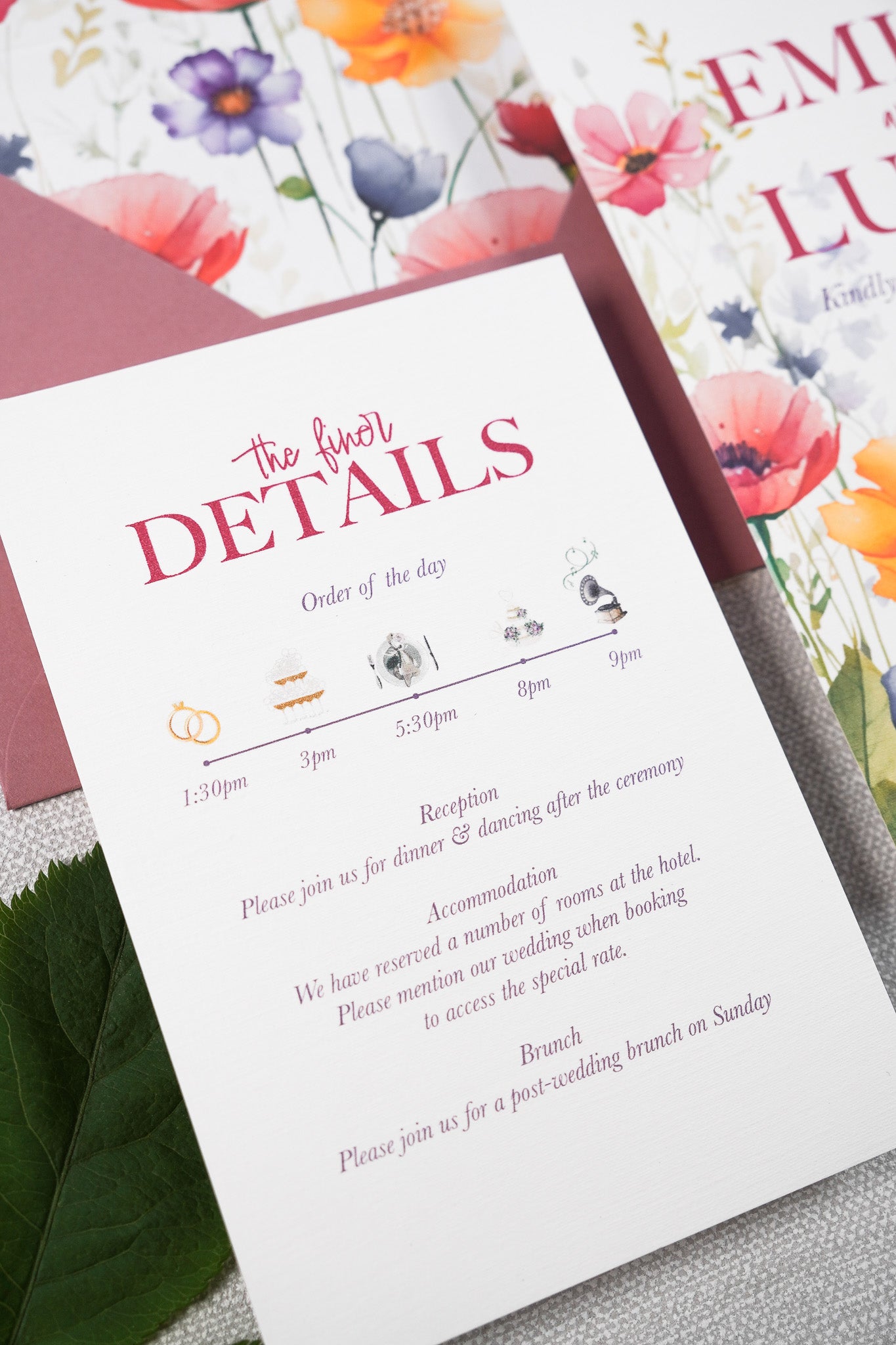 A close up on a floral wedding invitation with a detail card. The card features an illustrated timeline of the wedding day.
