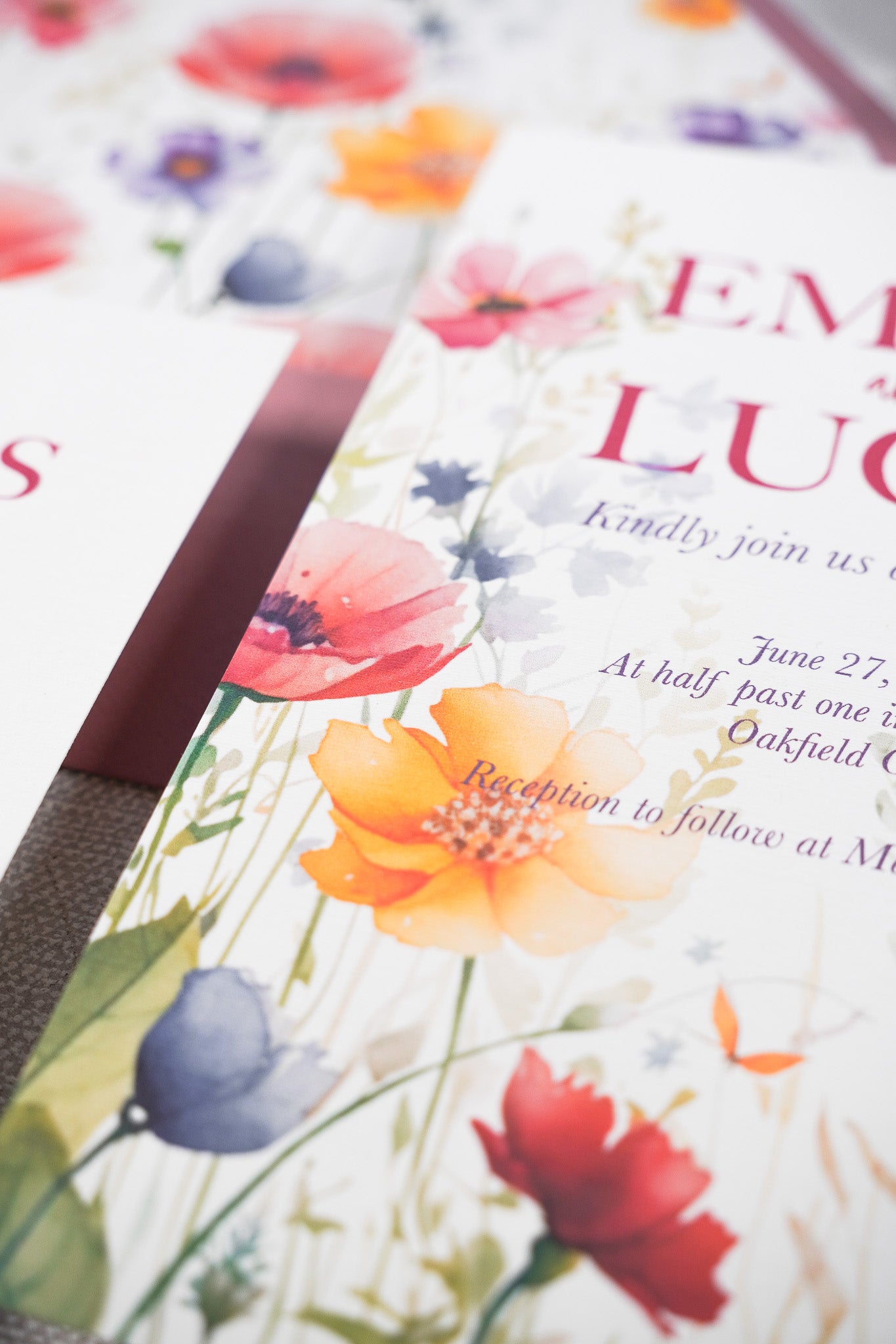 Close up on a floral wedding invitation with a rose pink envelope. The invitation is in a hanpinted garden print in vivid colors.