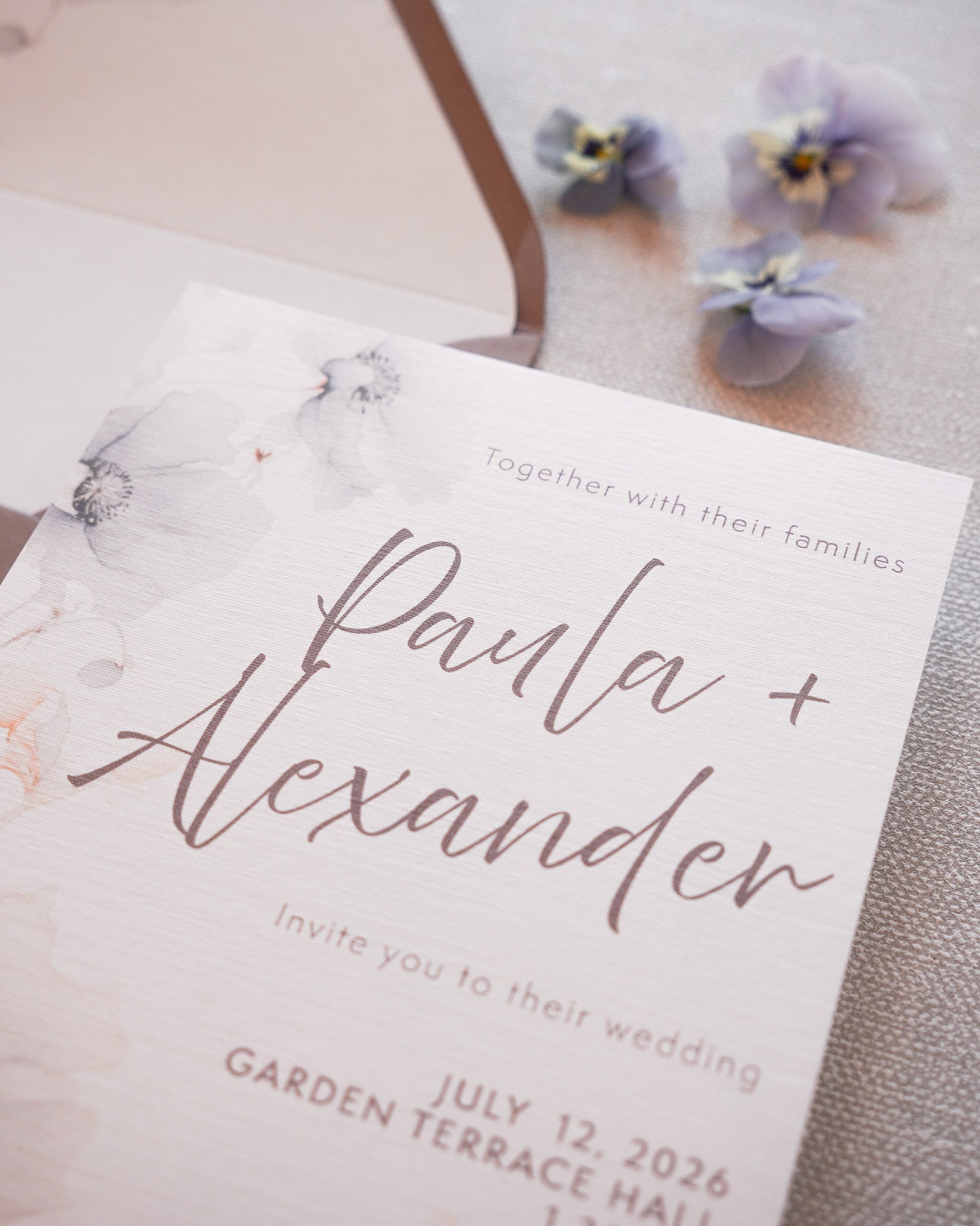 A closeup of a wedding invitation in a soft floral print. 