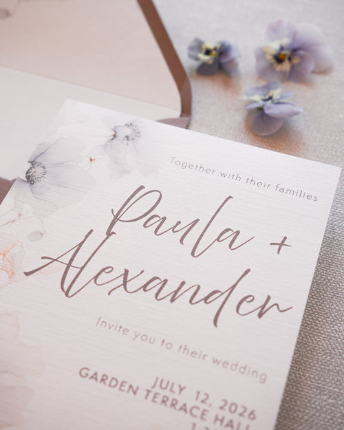 A closeup of a wedding invitation in a soft floral print. 